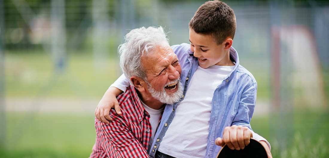 A grandfather plays with his grandson in a backyard